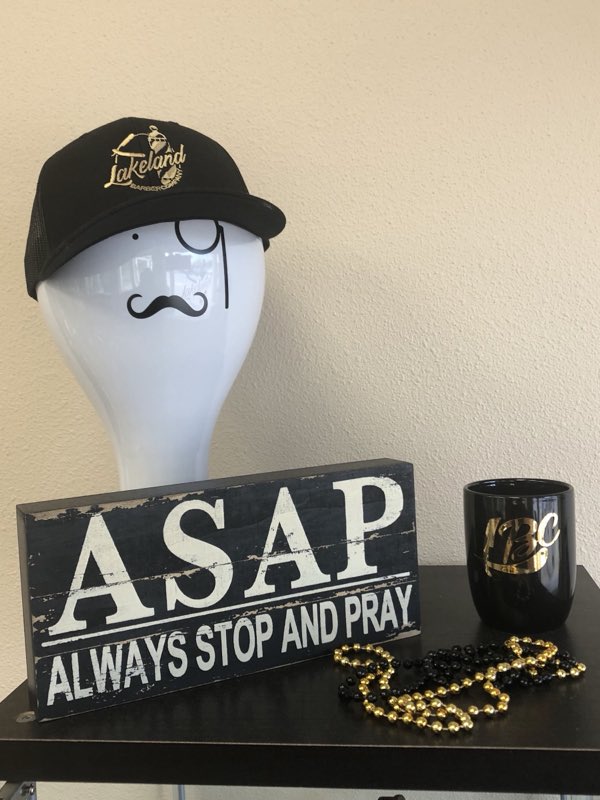 Shop merchandise - a black Lakeland Barber Company cap with gold embroidery and a black-and-gold mug