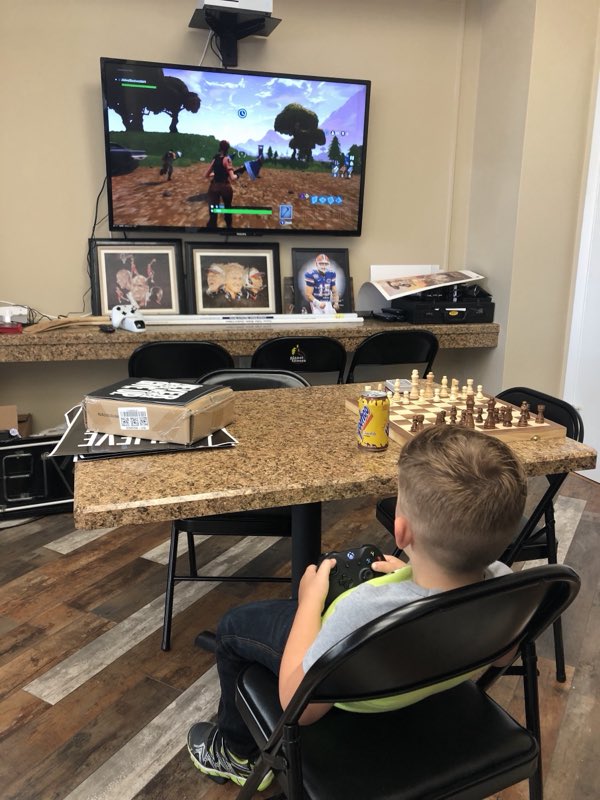 The kids' corner - a boy plays a game on the wall TV next to a chess board